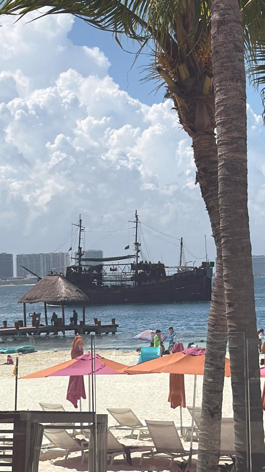 חופשה במקסיקו Palm trees, beach umbrellas and a ship offshore on the Cancun coast